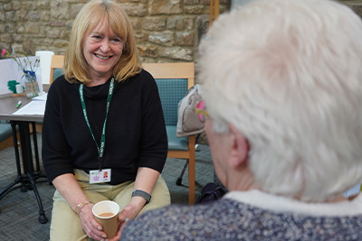 A counsellor sits with an elderly woman for a 1 to 1 session.